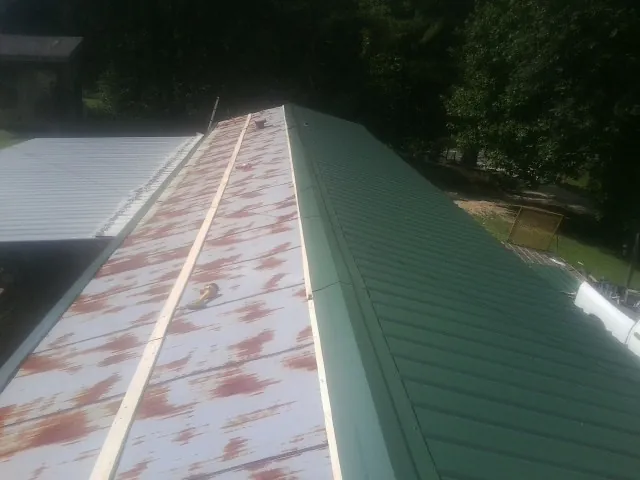 Old rusted panels beside newly installed green metal roofing — Wind Damage Roof Repair by Roofing Brothers in Maiden