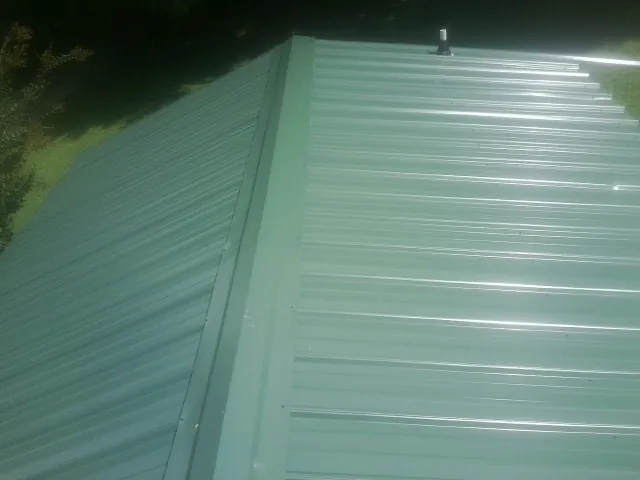 New green metal panels meeting at the ridge of a roof — Flat Roof Repair work by our crew in Maiden