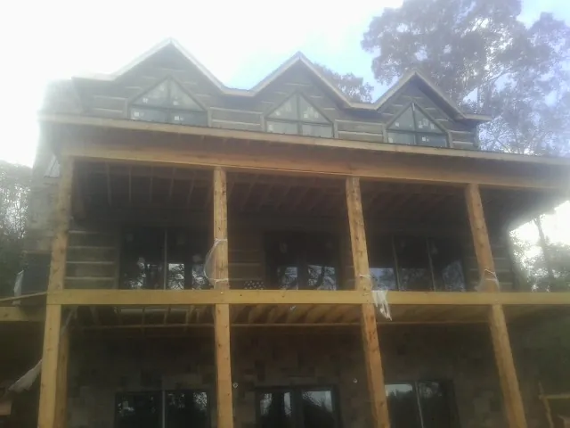 Dormers and porch framing on a large log home under construction — Roof Coating work by our crew in Maiden