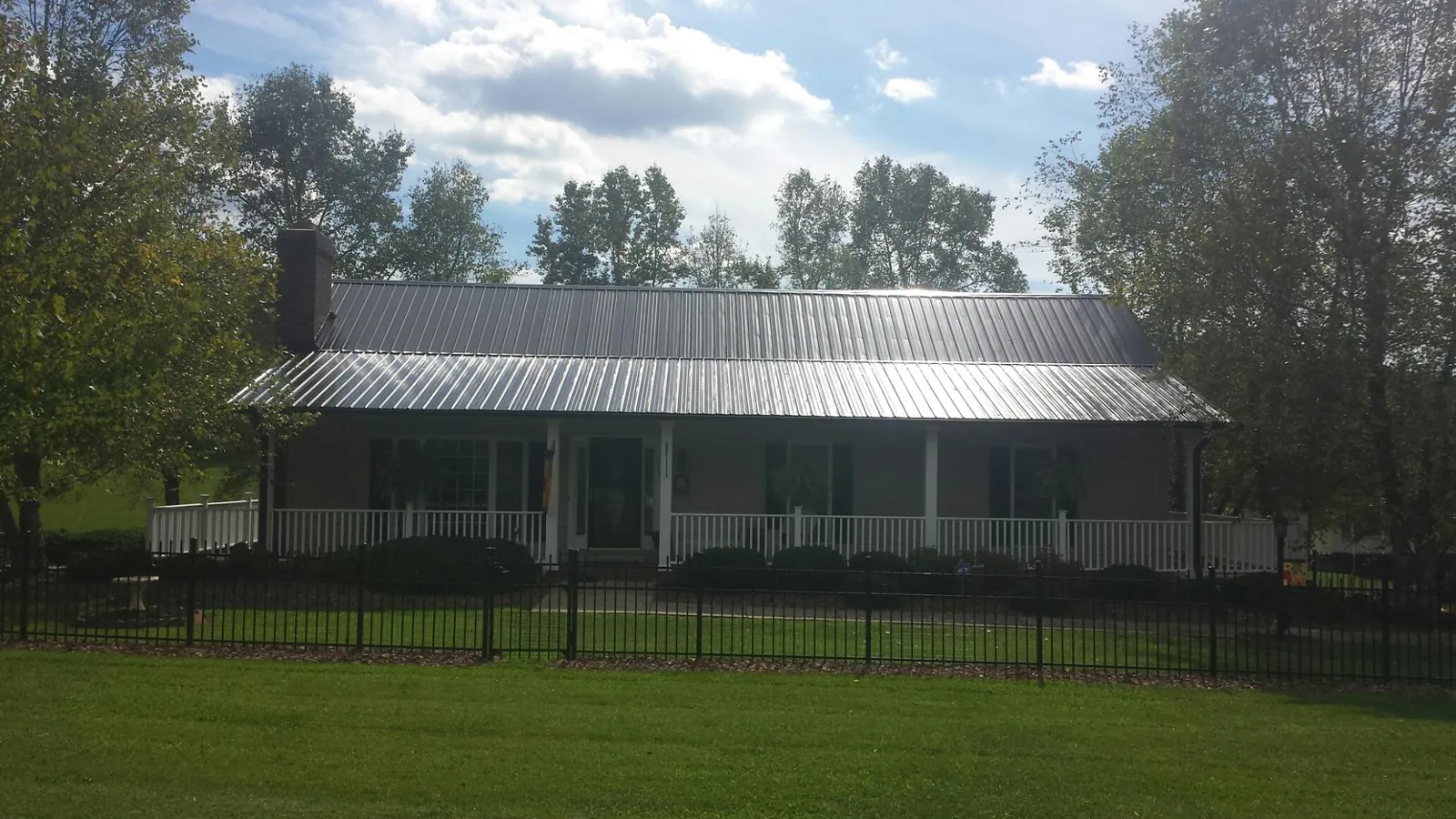 Gray metal roof on a brick ranch with a full width front porch — Gutter Guard Installation work by our crew in Maiden