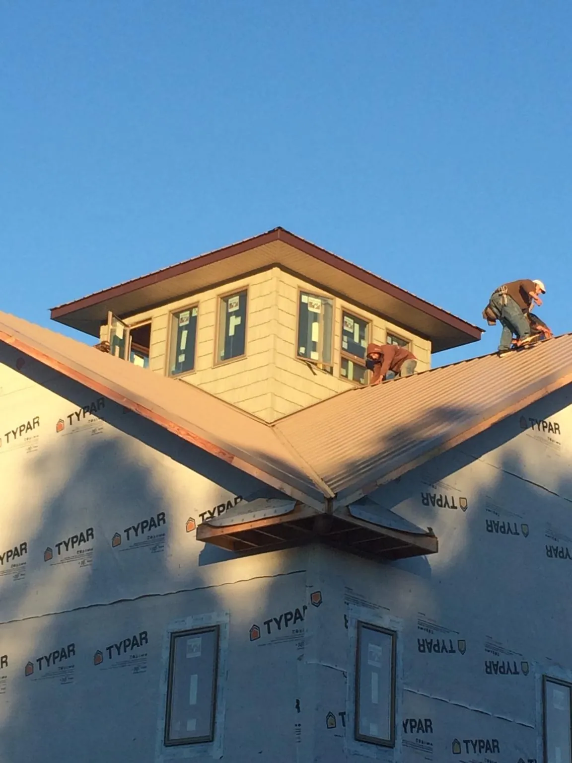 Roofers working around a rooftop cupola on a new metal roof at sunset — Roof Waterproofing in Maiden by Roofing Brothers